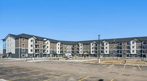 Warman apartment for rent - A large apartment complex with a parking lot in front.
