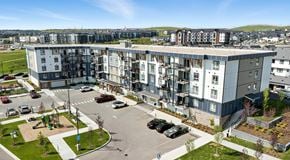 Calgary apartment for rent - A large apartment building with a parking lot in front of it.