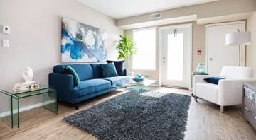 Portage La Prairie apartment for rent - A living room with a blue couch and a glass coffee table.