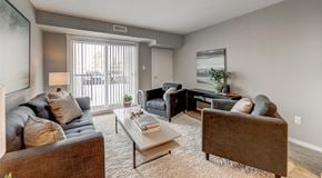 Edmonton apartment for rent - A open living room with a couch, coffee table and two chairs. A large sliding door with lots of natural light