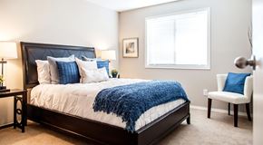 Edmonton apartment for rent - a bedroom with queen sized bed, night stands a chair and large window