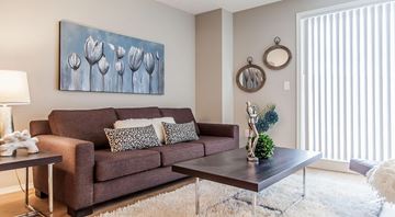 Edmonton apartment for rent - A living room with a brown couch, a painting of tulips, and a mirror on the wall.