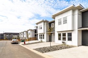Campbell River apartment for rent - A white house with a grey garage door is in front of a row of houses.