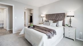 Lethbridge apartment for rent - A bedroom with a queen sized bed, a nightstand, and an entrance to a walk in closet