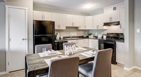 Edmonton apartment for rent - A open modern kitchen with light cabinets, black appliance and table set for four