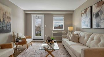 Campbell River apartment for rent - A living room with a white couch, a glass coffee table, and a painting on the wall.