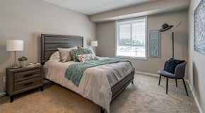 Sylvan Lake apartment for rent - A bedroom with a bed, nightstand, and chair.