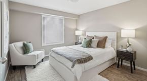 Medicine Hat apartment for rent - A bedroom with queen sized bed, night stands and chair. A big window with blinds