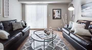 Winnipeg apartment for rent - A living room with two black leather couches and a glass coffee table.