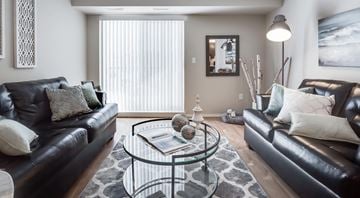 Winnipeg apartment for rent - A living room with two black leather couches and a glass coffee table.