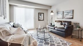 Winnipeg apartment for rent - A living room with two couches and a coffee table. A large glass sliding door leads to a balcony