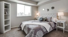 Winnipeg apartment for rent - A bedroom with queen sized bed, night stands and book shelf. large window with blinds