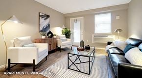 Port Alberni townhouse for rent - An Apartment living room with a couch, coffee table and chairs. A single patio door with windows, an AC unit sits below a standard sized window