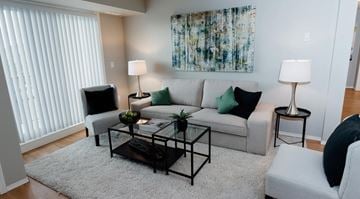 Winnipeg apartment for rent - A living room with a grey couch, a black coffee table, and a painting on the wall.