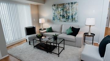 Edmonton apartment for rent - A living room with a grey couch, a black coffee table, and a painting on the wall.
