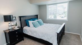 Edmonton apartment for rent - A bedroom with a bed, nightstand, and window.