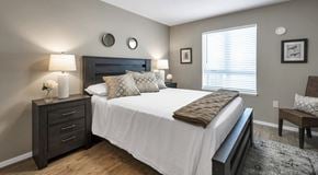Campbell River apartment for rent - A bedroom with queen sized bed, night stands and chair. A big window with blinds and lots of natural light