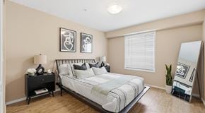 Lethbridge apartment for rent - A bedroom with a large bed, two nights stands and floor length mirror. A large window with blinds  is against one wall