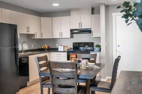 Campbell River apartment for rent - A modern kitchen with a black refrigerator and wooden chairs around a dining table.