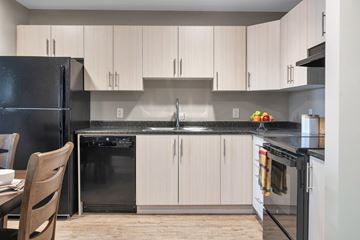 Campbell River apartment for rent - A kitchen with a black refrigerator and white cabinets.