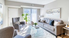 Edmonton apartment for rent - A bright living room with a couch and chairs, a coffee table and some end tables. I large sliding glass door with blinds