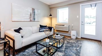 Comox apartment for rent - A modern living room with a white couch and a glass coffee table.