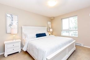 Parksville apartment for rent - A bedroom with a white bed and a white nightstand with a lamp.
