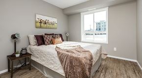 Saskatoon apartment for rent - A bedroom with a queen sized bed and two night stands, with a large window