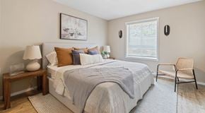 Kamloops apartment for rent - A large bright bedroom with queen sized bed, night stands and a chair.