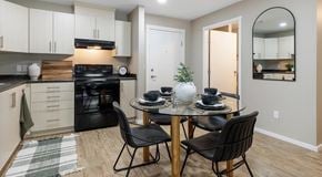 Kamloops apartment for rent - A bright kitchen with light cabinets and black appliances, a round table sits in the centre with four chairs