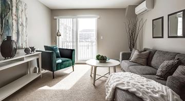 Edmonton apartment for rent - A living room with a grey couch, a green armchair, a white coffee table, and a large painting on the wall.