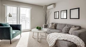 Winnipeg apartment for rent - A living room with a sectional, coffee table and chair. A glass sliding door with lots of natural light