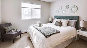 Edmonton apartment for rent - A bedroom with queen sized bed, night stands and a chair