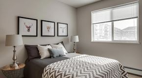 Saskatoon apartment for rent - A bedroom with large bed, nightstands and large window with blinds