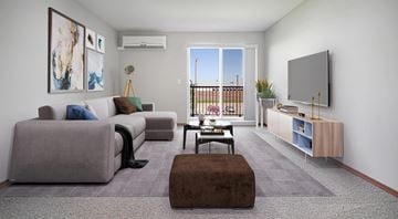 Winnipeg apartment for rent - A living room with a grey couch, a brown ottoman, and a television on the wall.