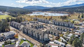 Cranbrook apartment for rent - A large building complex with a lake and mountains in the background.