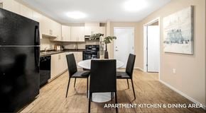 Campbell River apartment for rent - An apartment kitchen with light cabinets, black appliances and a kitchen table in the centre