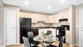 Saskatoon apartment for rent - A modern bright kitchen with light cabinets, black appliances, a pantry and kitchen table set for four
