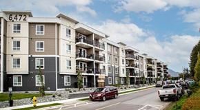 North Cowichan apartment for rent - An apartment building with lots of windows and balconies sits next to a street with street parking