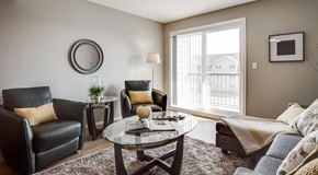 Edmonton apartment for rent - A living room a small sectional, coffee table and two arm chairs. A large glass sliding door sits next to them