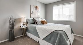 Edmonton apartment for rent - A bedroom with a bed, nightstand, and a large window.
