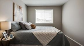 Edmonton apartment for rent - A bedroom with a bed, a nightstand, and a window.