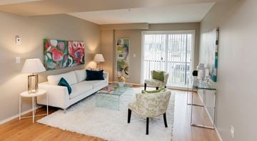 St. Albert apartment for rent - A living room with a white couch and a green armchair.