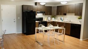 St. Albert apartment for rent - A kitchen with dark cabinets, black appliances and light counters. A square table sits in an opening in the center.