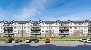 Winnipeg apartment for rent - A large apartment building with small green space separating it and a parking lot