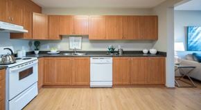 Winnipeg apartment for rent - A large open kitchen with lots of wooden cabinets and white appliances