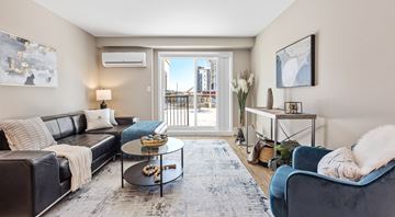 Orleans apartment for rent - A living room with a black leather couch, a blue velvet armchair, a coffee table, and a painting on the wall.