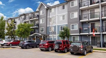 Winnipeg apartment for rent - A row of cars parked in a parking lot in front of apartment buildings.