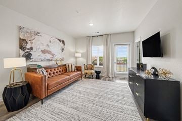 Colorado Springs apartment for rent - A living room with a brown leather couch, a black cabinet, and a large abstract painting on the wall.