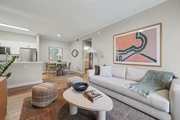 Lakewood apartment for rent - A modern living room with a white couch and a large abstract painting on the wall.